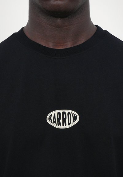 Camiseta de algodón negra con cuello redondo acanalado, que presenta un logo ovalado central que dice "BARROW" en una fuente estilizada en blanco y negro.