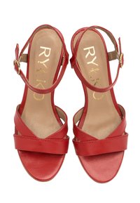 Czerwone skórzane sandały z szerokim paskiem na palcach i cienkim paskiem na kostce. Zawierają złotą klamrę i teksturowaną podeszwę.