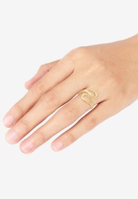 Goldfarbener, doppelschleifiger Ring an einer Hand, mit einer glatten, polierten Oberfläche und offenem Design. Einfacher, moderner Stil ohne Verzierungen.