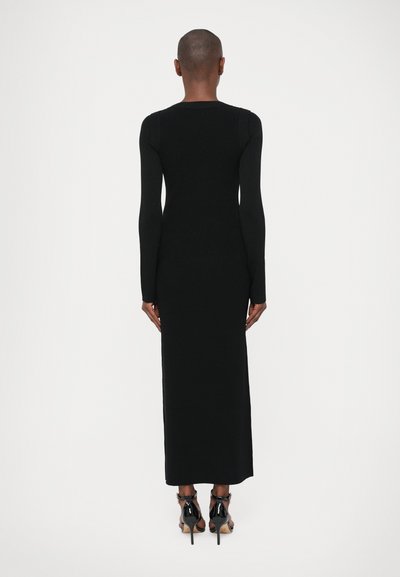 Must mustriga mustriga pealt valge diivaniga dress, millega on ühendatud mustad kõrged kontsad.