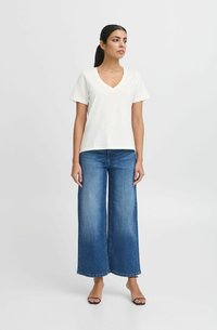 White short-sleeve V-neck t-shirt paired with wide-leg blue denim jeans. Soft fabric texture; seamless design with no visible patterns or accents.