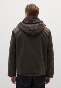 Braune, kapuzenbesetzte Jacke mit einem lässigen Design. Verfügt über einen strukturierten Stoff und einen elastischen Saum. Die Rückansicht zeigt einfache Nähte und Taschen.