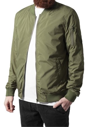 Veste bomber vert olive avec une fermeture éclair à l'avant, des poignets et un ourlet côtelés, et une poche latérale sur la manche gauche. Tissu lisse et léger.