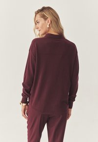 Burgundia pullover pika säärega, pehme tekstuuriga ja kraega. Omab sirget äärist ja lõdvet, mugavat istuvust seljaosas. Sobitub sobivate pükstega.
