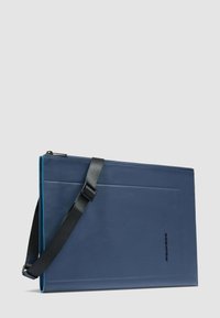 Bolsa rectangular azul para portátil con correa de hombro ajustable negra y cierre de cremallera, mostrada sobre un fondo liso gris claro.