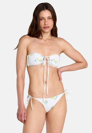 Bikini blanc avec des motifs floraux bleus et verts. Le haut présente un design bandeau avec un nouage central, et le bas comporte des liens latéraux réglables.