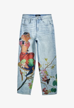 Jasnoniebieskie dżinsy z detalicznym artystycznym nadrukiem przedstawiającym siedzącą kobietę, liście, kwiaty i ptaki wzdłuż nogawek.