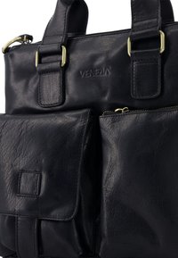 Černá kožená taška s nastavitelnými popruhy, několika zipovými přihrádkami a přední kapsou se klopou. Obsahuje hardware v zlatém tónu a vyražené logo.