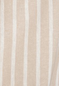 Tessuto rigato beige e bianco con una trama texturizzata, caratterizzato da strisce verticali alternate di larghezze variabili.