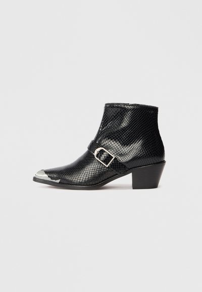 Black ankle boots made of textured material with a scaled pattern, featuring a silver-toned toe cap and a side buckle accent.