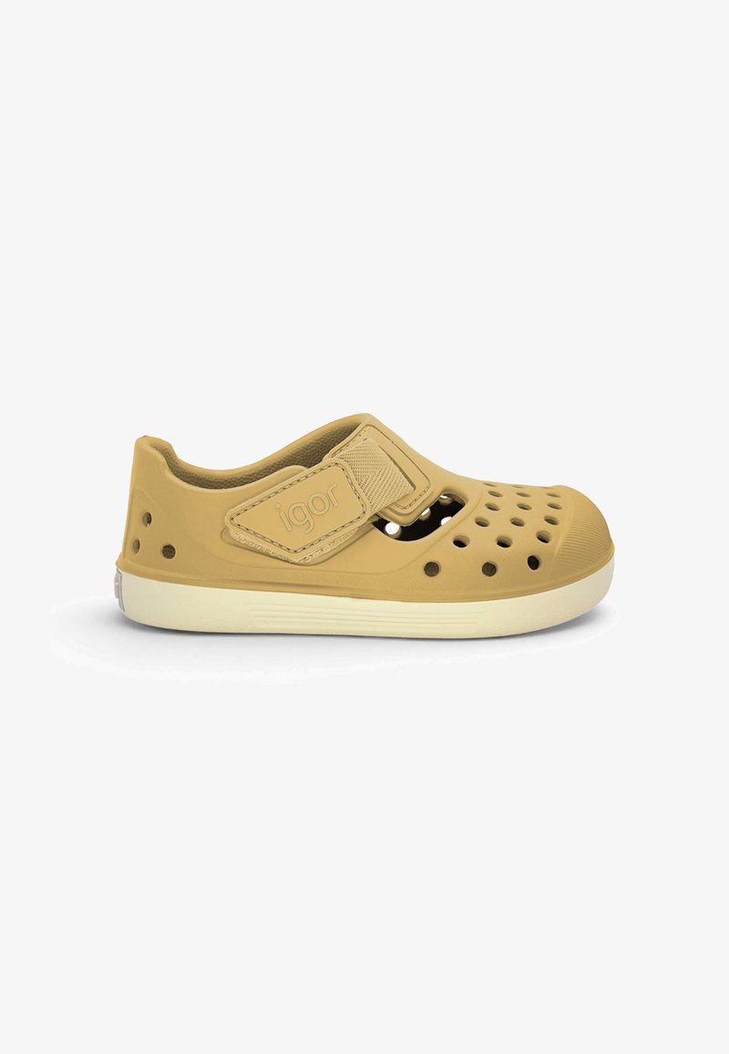 Chaussure légère marron clair à enfiler avec des trous de ventilation, bride ajustable étiquetée "igor," et semelle blanche, conçue pour un usage décontracté.