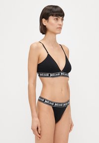 Set di lingerie nera composto da un bralette triangolare con spalline regolabili e un perizoma abbinato, entrambi caratterizzati da accenti del logo 'justcavalli'.
