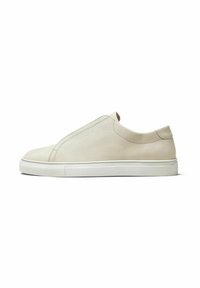 Light beige slip-on sneakers made of textured leather. Features a white rubber sole and minimalistic design with no visible laces.
