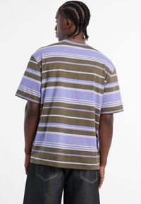 Gestreiftes T-Shirt in mehreren Farben mit breiten horizontalen Streifen in Olivgrün, Lavendel und Weiß. Hergestellt aus weicher Baumwolle mit einer lässigen Passform.