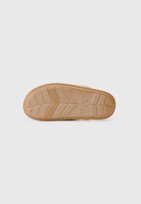 Potplat smeškanih Crocs natikača sa teksturiranim uzorkom za prianjanje i vidljivim Crocs logom na bijeloj podlozi.