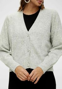 Světlý šedý kardigan vyrobený z měkkého materiálu, s véčkovým výstřihem, žebrovanými manžetami a lemem a třemi dekorativními knoflíky vpředu.
