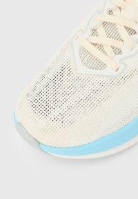 Αθλητικό παπούτσι από ανοιχτό κρεμ δίχτυ με υφή, διακοσμημένο με απαλές μπλε λεπτομέρειες και κρεμ κορδόνια. Στρογγυλερή μύτη με μαλακή σόλα για άνεση.