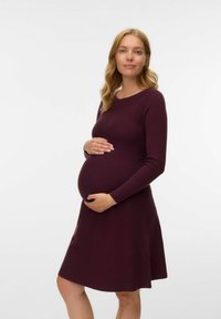 Nėštumo suknelė giliu burgundišku atspalviu, ilgomis rankovėmis, apvaliu iškirpimu, prigludusia liemene, plačia sijonu, pakeltu tekstūra, siekianti kelių ilgį.