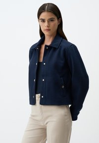 Dunkelblau verkürzte Jacke aus weichem Stoff, mit Hemdkragen, Knopfverschluss und seitlichen Taschen mit goldenen Akzenten.