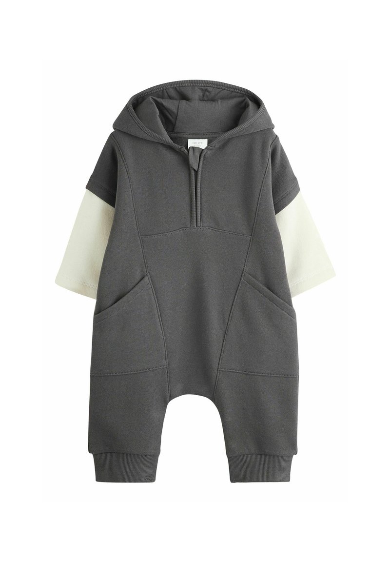 Grauer Kapuzenoverall mit kurzen Ärmeln, ausgestattet mit vorderen Taschen und einem Viertelreißverschluss. Der Stoff hat eine glatte Textur mit kontrastierenden Cremeakzenten.