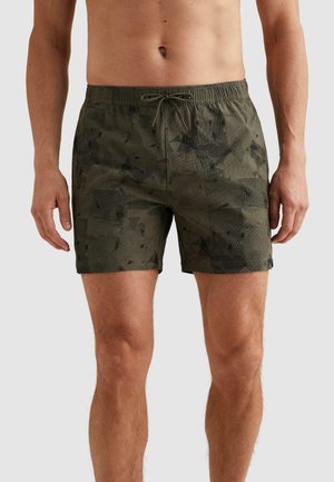 Mužský trup a nohy v tmavozelených kraťasoch na plávanie s maskáčovým vzorom, elastickým pásom a šnúrkou na jednoduchom pozadí.