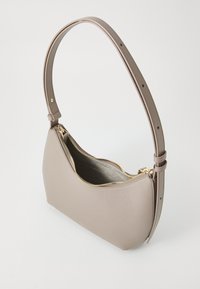 Sac à main en cuir beige de taille moyenne avec une forme incurvée, fermeture éclair dorée et une bandoulière ajustable. Texture douce avec un design minimal.