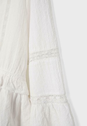 Tissu blanc texturé avec détails en dentelle et sections froncées, probablement une partie d'une manche ou d'une robe.