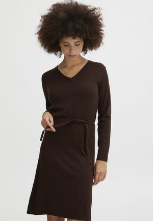 Braunes langärmliges Kleid mit V-Ausschnitt und Bindedetail, das eine taillierte Silhouette und einen knielangen Saum aufweist. Weicher Stoff und minimalisches Design.