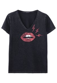 Musta V-kaula-aukkoinen t-paita, valmistettu farkkukankaasta. Siinä on kuva punaisista huulista, joissa näkyy valkoiset hampaat ja punaiset salamaniskut.