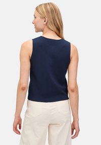 Marineblaues ärmelloses Oberteil mit rundem Halsausschnitt und tailliertem Design, aus einem glatten Stoff gefertigt, vor einem einfarbigen Hintergrund dargestellt.