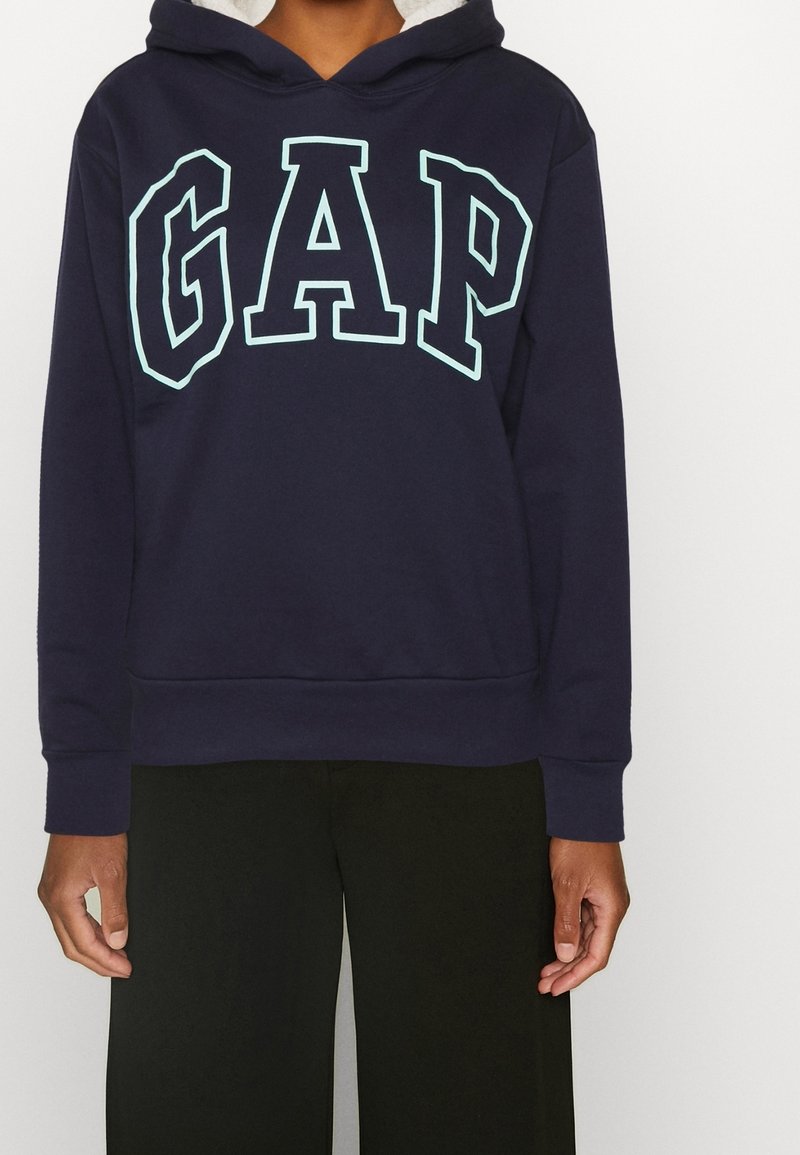 Sweat à capuche en coton bleu marine avec un grand logo "GAP" bleu clair sur le devant, doté d'une capuche à cordon de serrage et de poignets et ourlet côtelés.