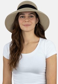 Breiter Strohhut in hellem Beige mit einem schwarzen Band. Das Design zeichnet sich durch eine strukturierte Webart aus, die Sonnenschutz und Belüftung bietet.