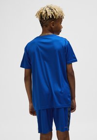 Blå atletisk t-shirt med korta ärmar, slät textur, kombinerad med blå shorts med kontrasterande svarta sidsstreck.