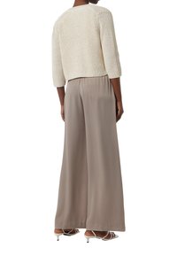 Pull en tricot crème à manches trois-quarts associé à un pantalon large beige fluide et des talons blancs à brides, vu de dos.