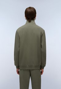 Sudadera ligera de color verde oliva con alto cuello, puños y dobladillo acanalados, hecha de tela suave; vista desde la parte posterior.