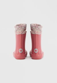 Ζευγάρι ροζ καουτσούκ μπότες βροχής με λουλούδια στα μανίκια, προβαλλόμενο από πίσω σε λευκό φόντο.