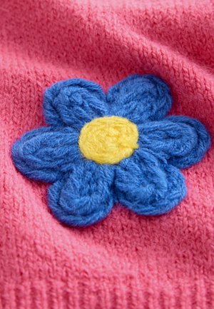 Tissu tricoté rose avec une application florale bleue texturée, présentant un centre jaune. La fleur a un effet 3D avec des pétales superposés.