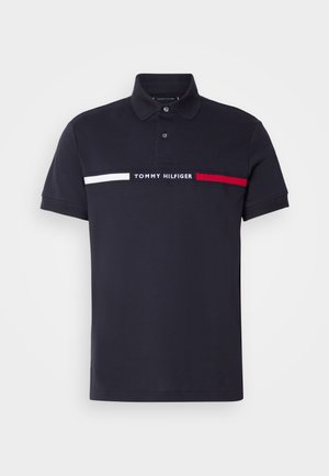 Navyblauwe polo gemaakt van katoen, met een kraag en drie knopen. Horizontale strepen in wit en rood met "TOMMY HILFIGER" geborduurd.