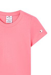 Rövid rózsaszín Champion póló kerek nyakkivágással, méretjelzés a gallér belső oldalán, és Champion logó a bal ujján.