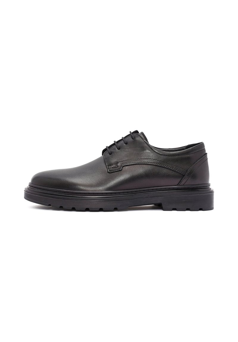 Chaussures habillées en cuir noir avec une surface lisse, un bout rond et une semelle en caoutchouc à profil bas dotée d'un motif de semelle texturé.