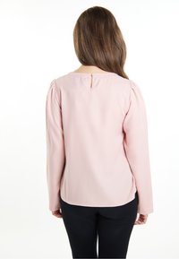 Langærmet bluse i blødt pink stof med detalje i ryggen, der har nøglehul, med en afslappet pasform og subtile puffede skuldre.
