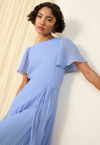 Robe plissée bleu clair avec de courtes manches volantées et une ceinture à la taille ; fabriquée dans un tissu lisse avec une silhouette fluide et une légère brillance.