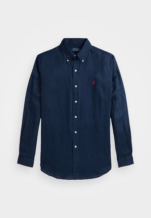 Chemise bleu marine à manches longues avec boutons, col et petit petit logo rouge brodé sur la poitrine gauche.