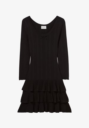 Abito nero in maglia a coste con scollatura ampia, maniche lunghe e orlo svasato con volant a tre livelli. Include un fiocco decorativo.