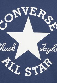 Marineblauwe katoenen t-shirt met een grote witte ster en de tekst "CONVERSE CHUCK TAYLOR ALL STAR" in verschillende letterstijl.