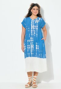 Blå och vit tie-dye klänning med korta ärmar, V-ringning och sidofickor, som har en flödande design och en fåll som övergår till solid vit.