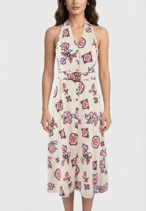 Robe sans manches à col licou avec boutonnage sur le devant, taille ceinturée et motifs floraux roses sur tissu crème, portée par une femme debout.