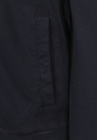 Marineblauwe sweatshirtstof met een textuur, voorzien van een zijzak met gestikte rand, ribgebreide zoom en manchetten.