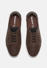 A barna b�őrsneaker alacsony profilú kialakítással, hálós betétekkel és fehér gumitalppal rendelkezik. Fűzőket és ortolite párnázást tartalmaz.