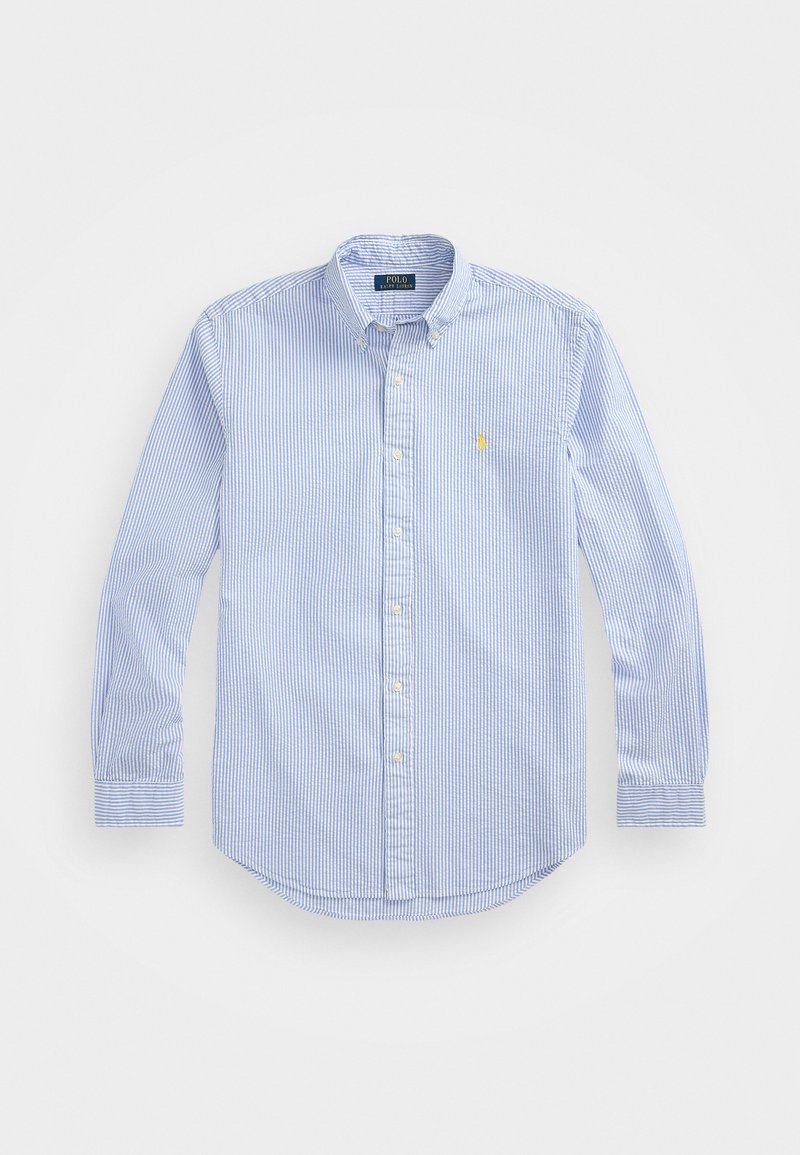 Modrá a biela pruhovaná košeľa s dlhým rukávom na gombíky, s ostrým golierom, zaobleným lemom a vyšitým logom na ľavej strane hrudníka.